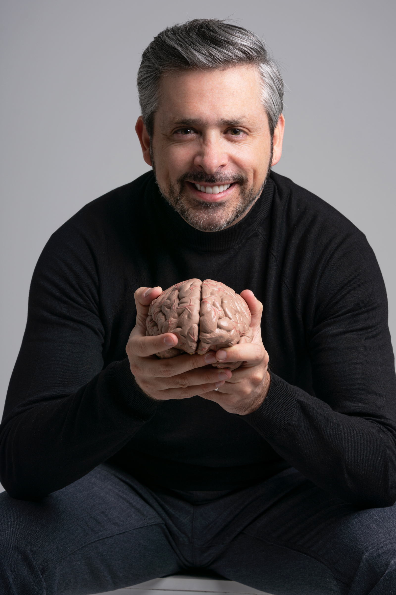 Dr. (H.C.) Esteban Castillo, arquitecto del ecosistema Artesanos®, sosteniendo un modelo anatómico de cerebro humano